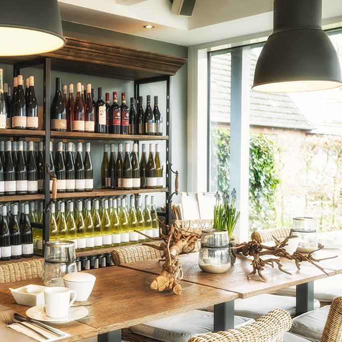 Tisch mit Wein Regal im Hintergrund | Hotel Leegerpark Greetsiel